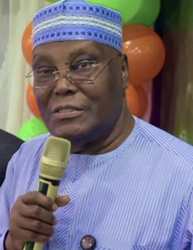 Atiku Abubakar in a blue cap and striped kaftan speaks into a microphone at an event