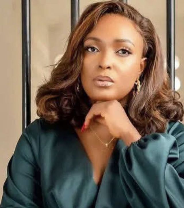 Blessing CEO in a dark green satin top, resting her chin on her hand