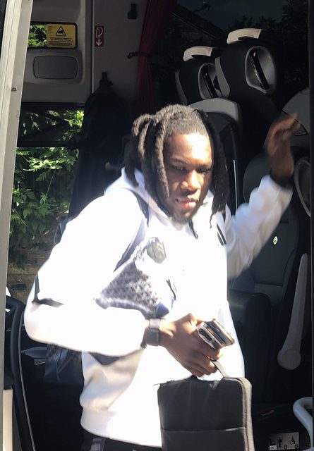 Calvin Bassey in a white hoodie stepping off a team bus