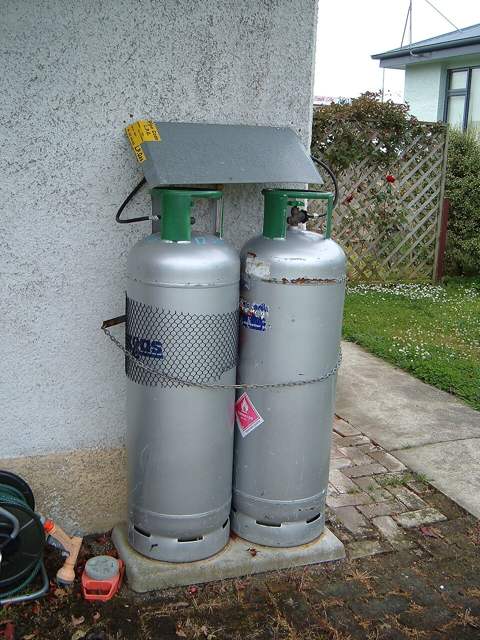 Two cooking gas cylinders against a wall