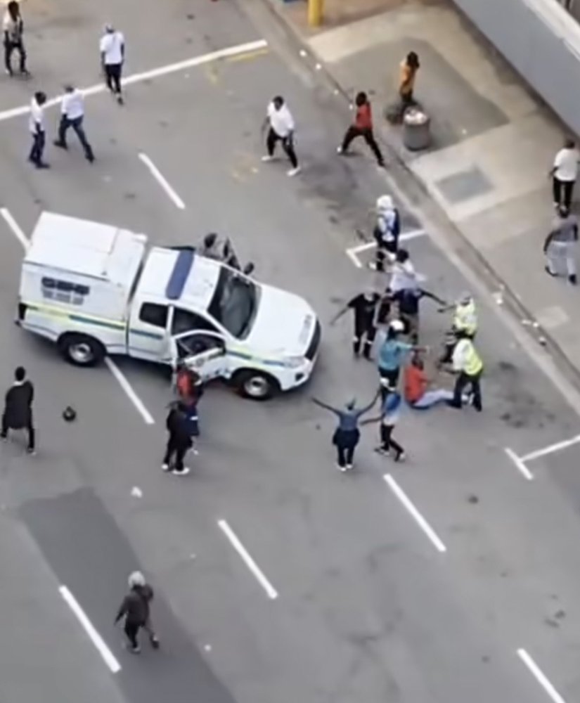 Aerial view of a crowd and a police van on a street in Durban during an attack