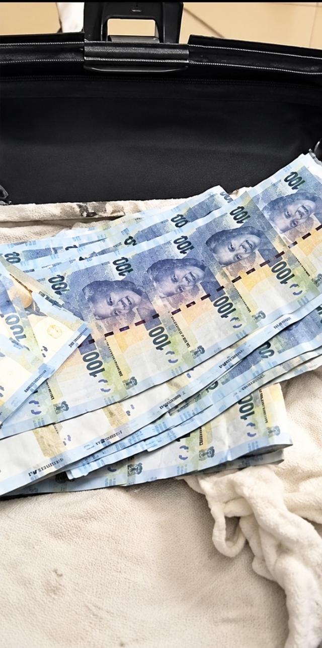 South African R100 banknotes spread out in an open black bag